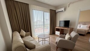Una habitación de hotel moderna con sofá, televisión y cama.