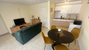 A living room with a sofa, TV, and a dining area with a table and chairs.