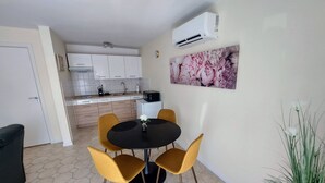 A compact kitchen with white cabinets, a black countertop, and a microwave.