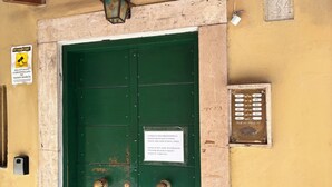 A green door with a sign requesting no brush to be left on the road. - Lola's House (Roma)