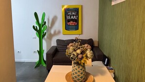 A small dining area with a table and chairs, a green decorative plant, a framed Heinz Beanz can, and a wall-mounted air conditioner. - Lola's House (Roma)