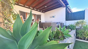 A modern house with a covered patio, outdoor seating, and various plants. - Casa Maracuya (Castillo Caleta de Fuste)