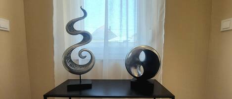A room with a black table displaying two metal sculptures.