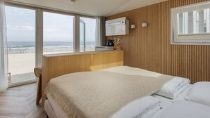 A bedroom with a large bed, a wooden desk, and a view of the beach. - Beach House in Zandvoort With Sea View (Zandvoort)