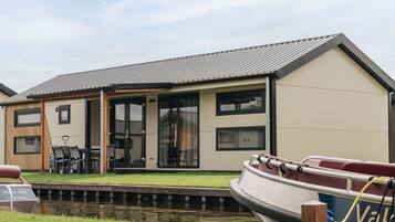 A modern house with a flat roof, large windows, and a dock with a boat.