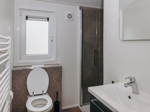A bathroom with a toilet, a sink, a shower, and a window. - Nice and Cosy Chalet With ac and Sloop (Giethoorn)