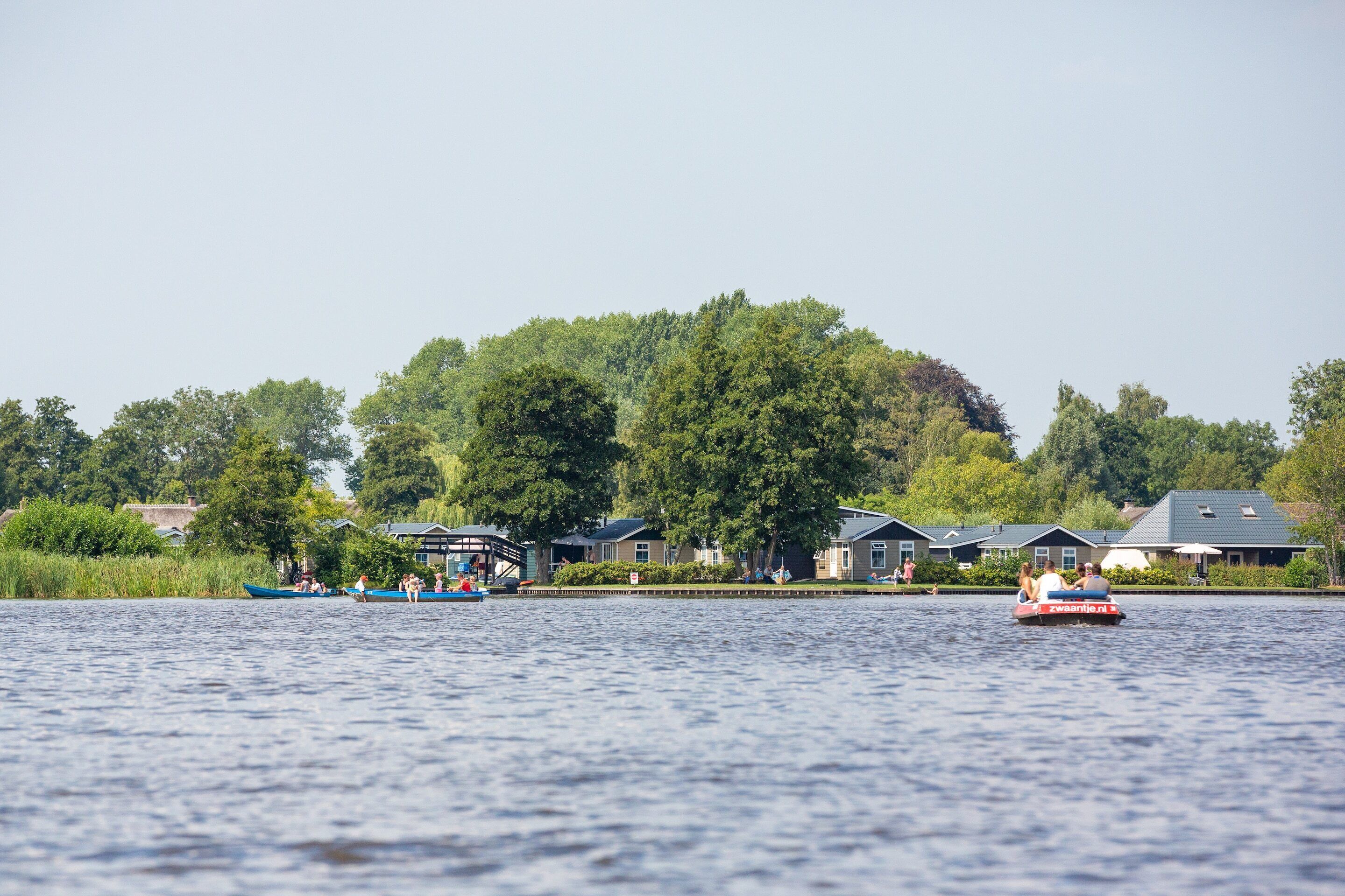 Un lac paisible, avec des bateaux et des maisons en arrière-plan.