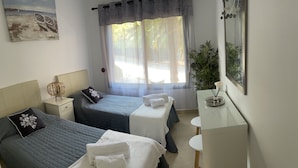 A hotel room with two beds, a bedside table with a lamp, a small table with a vase, and a large mirror. - Luxury complex 2 bed apartment with 5 pools and close to beaches, marina & golf (MANILVA)