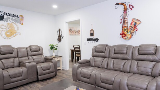 Ein modernes Wohnzimmer mit zwei braunen Ledersofas, einem Couchtisch und Wanddekorationen, darunter ein Saxophon und eine Gitarre.