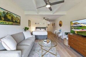 Una sala de estar moderna con un sofá, una mesa de centro de vidrio, un televisor y un ventilador de techo.