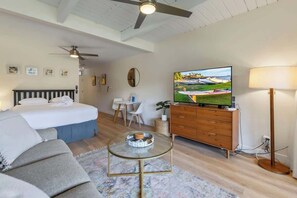 Un dormitorio con cama, televisor, cómoda y ventilador de techo.