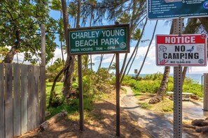 A beach park sign with park hours and a no camping notice.