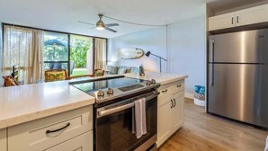 Una cocina moderna con horno empotrado, refrigerador de acero inoxidable y un amplio ventanal con cortinas.