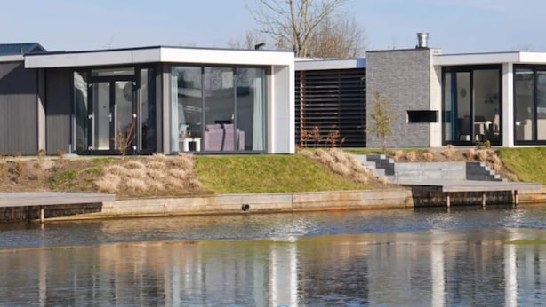 A modern house with large glass windows, a stone facade, and a small garden. - Chalet on the Water at the Beautiful Veluwemeer (Nunspeet)