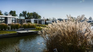 A modern building with a reflective glass facade, a small water feature, and surrounding greenery. - Chalet on the Water at the Beautiful Veluwemeer (Nunspeet)
