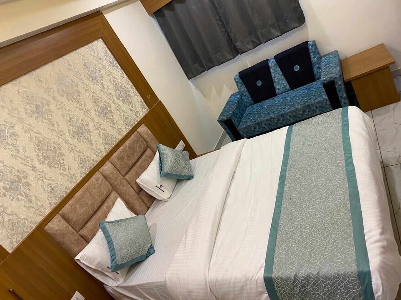 Ein ordentlich eingerichtetes Schlafzimmer mit einem Bett, Kissen, einem Nachttisch und einer Nachttischlampe.