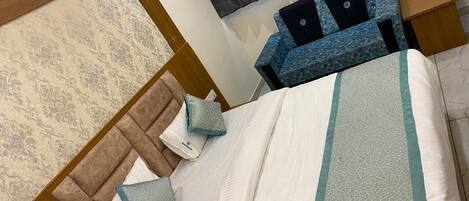 Ein ordentlich eingerichtetes Schlafzimmer mit einem Bett, Kissen, einem Nachttisch und einer Nachttischlampe.