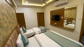 Ein Hotelzimmer mit zwei Betten, einem Deckenventilator, einer Klimaanlage, einem Fernseher und einem Spiegel.