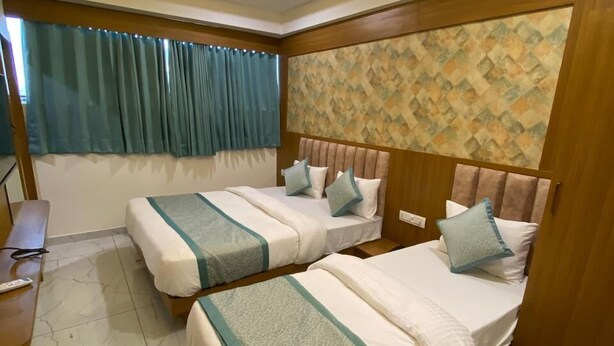Ein Hotelzimmer mit zwei Betten, einem Deckenventilator, einem Schreibtisch und einem Fenster mit Vorhängen.