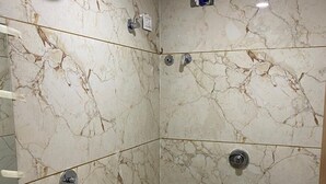 Ein Badezimmer mit Marmorwand, Dusche, Waschbecken und Toilette.