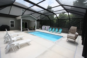 Une piscine extérieure couverte, dotée de chaises longues et d’une chaise.