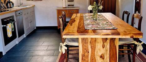 Una cocina rústica con una mesa de madera, una lámpara colgante y un ventanal.