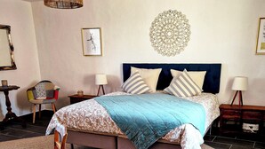 Een slaapkamer met een bed, een stoel, een tafel en een decoratief wandobject.