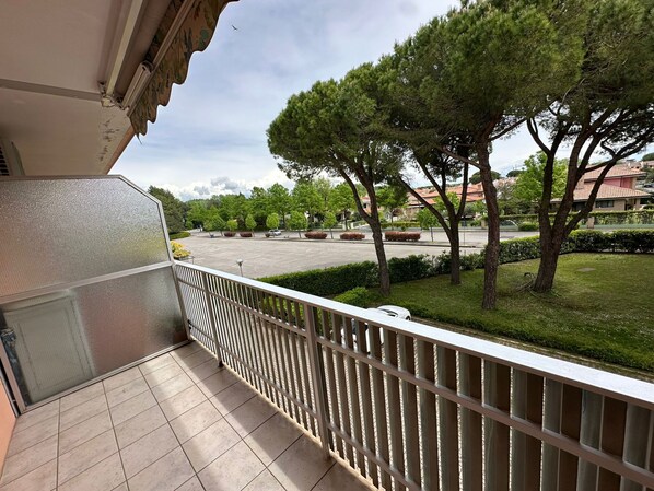 Ein Balkon mit Blick auf einen Parkplatz, Bäume und Gebäude im Hintergrund.