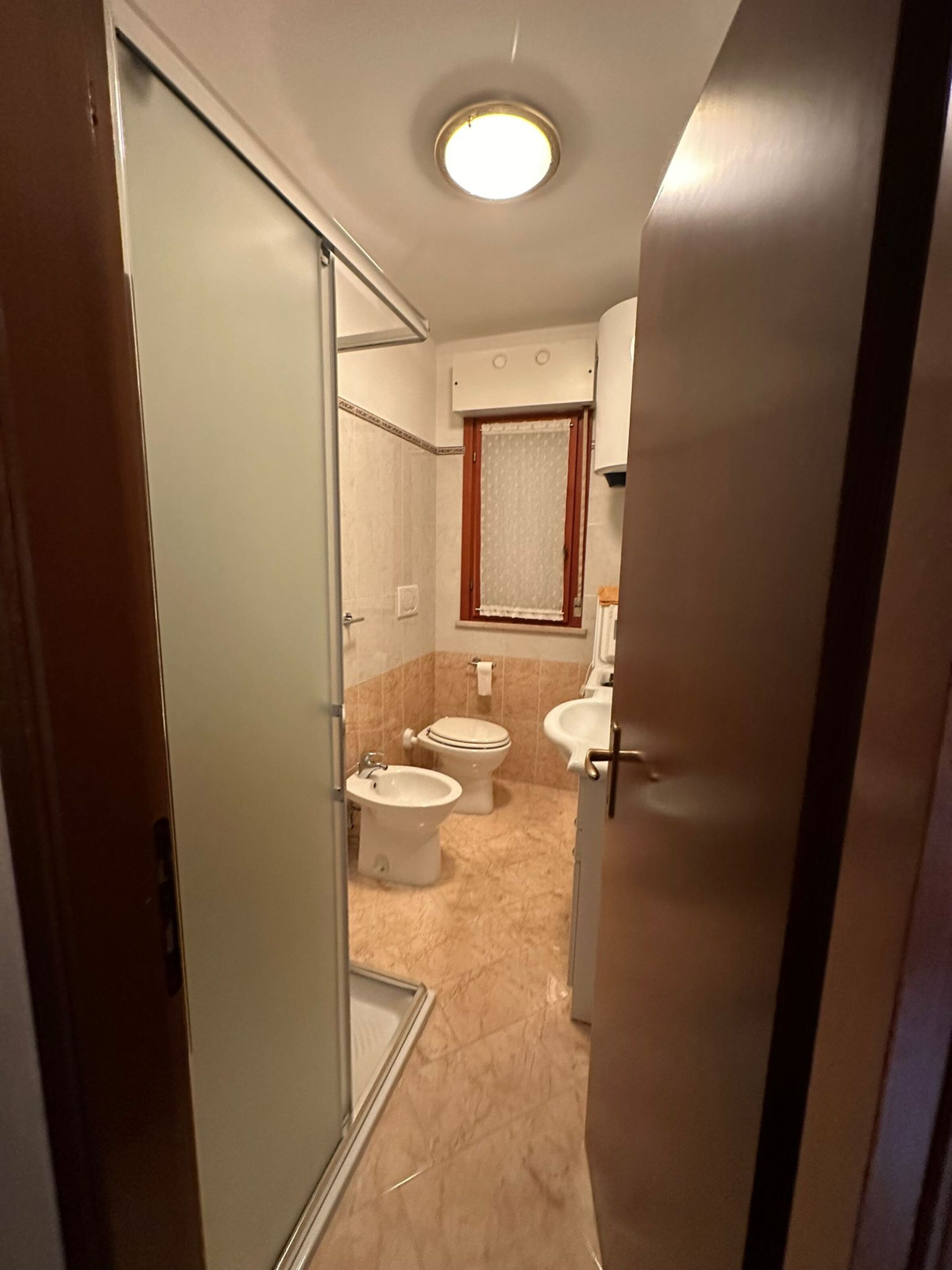 A bathroom with a shower, two toilets, a sink, and a mirror.