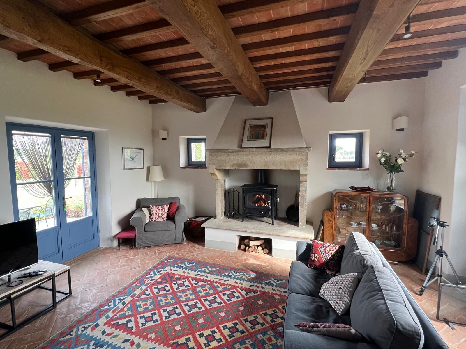 A cozy living room with a fireplace, a sofa, a TV, and a patterned rug.
