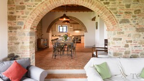 Un intérieur rustique avec une arche en pierre menant à une salle à manger et à une cuisine.