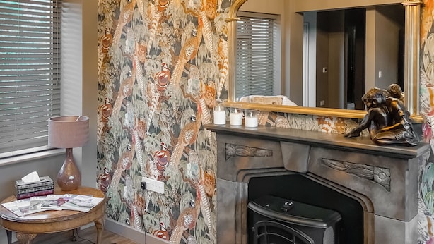 Une pièce chaleureuse avec une cheminée, un mur orné de motifs et un miroir.