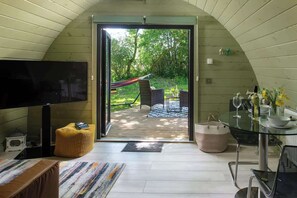 Un intérieur comprenant un téléviseur, un coin salon et une table en verre donnant sur l’extérieur.