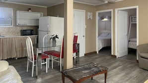 Un espacio habitable compacto con kitchenette, una zona de comedor con mesa y sillas, una cama y un pequeño rincón de descanso.