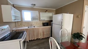 Una cocina compacta equipada con estufa, microondas, lavabo y refrigerador.