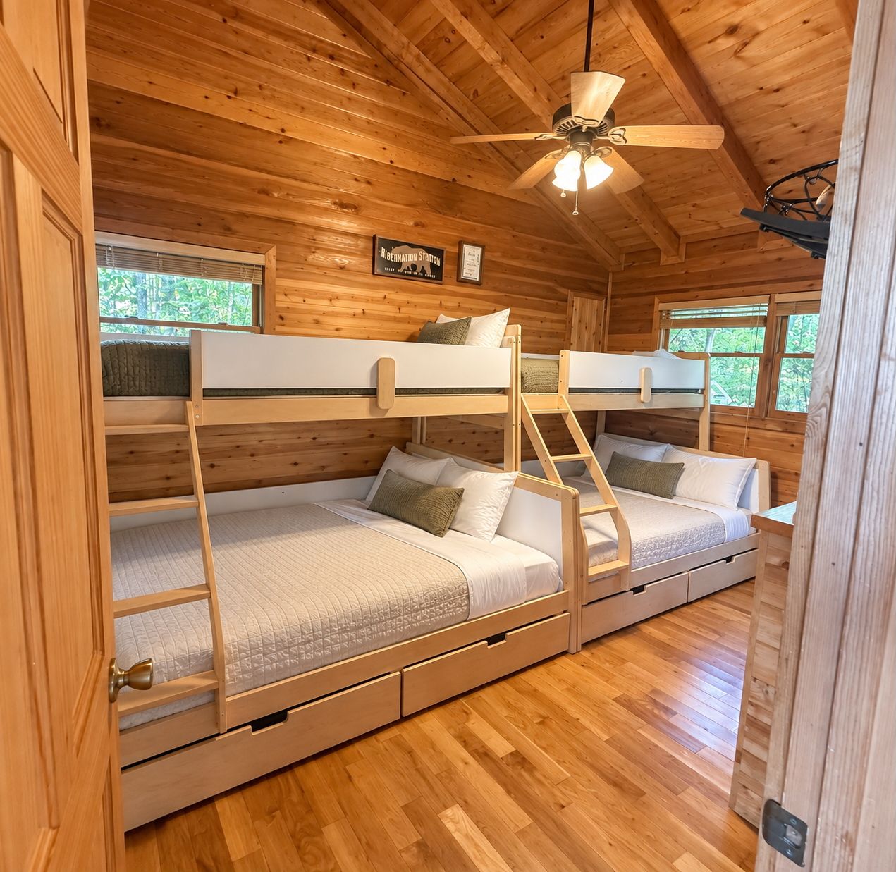 A cabin with bunk beds, a ceiling fan, and a window with a view of greenery.