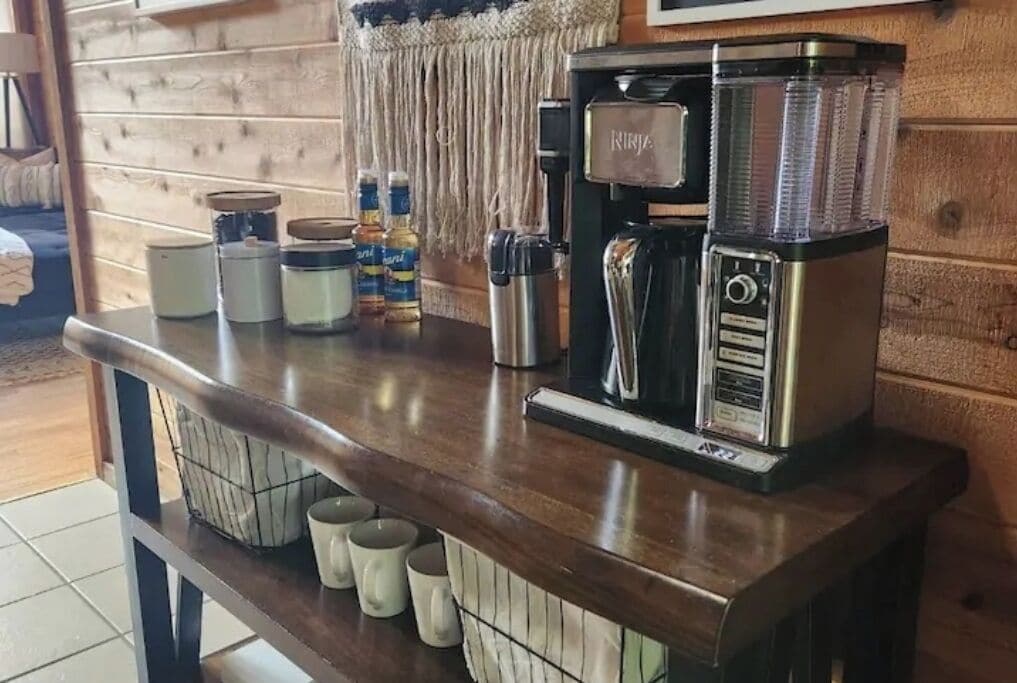 A kitchen counter with a coffee machine, jars, and mugs.