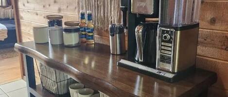 A kitchen counter with a coffee machine, jars, and mugs.