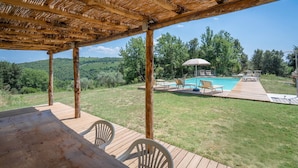 En træterrasse med pool, liggestole og pergola.