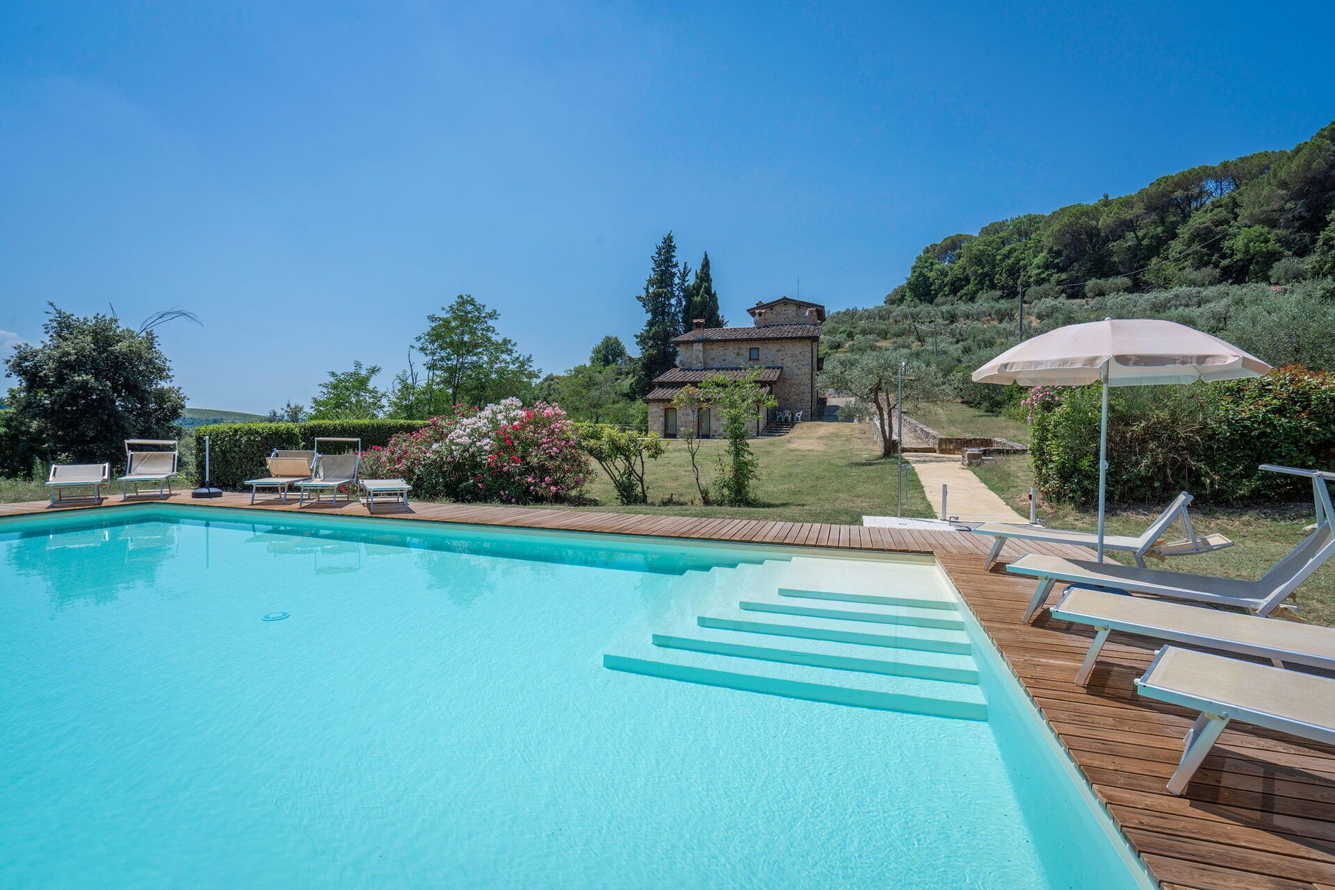 A swimming pool with lounge chairs and a wooden deck.