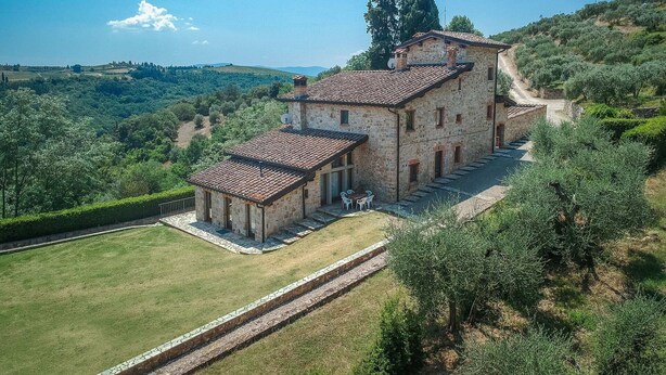 A stone building with a tiled roof, surrounded by a well-maintained lawn and trees. - Torre apt. ground and first floor (Poggibonsi)