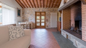 A cozy room with a stone wall, a fireplace, a wooden ceiling, and a tiled floor. - Torre apt. ground and first floor (Poggibonsi)