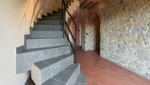 Un escalier avec des murs en pierre et un sol carrelé.