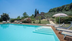 Une piscine avec des chaises longues et une terrasse en bois.
