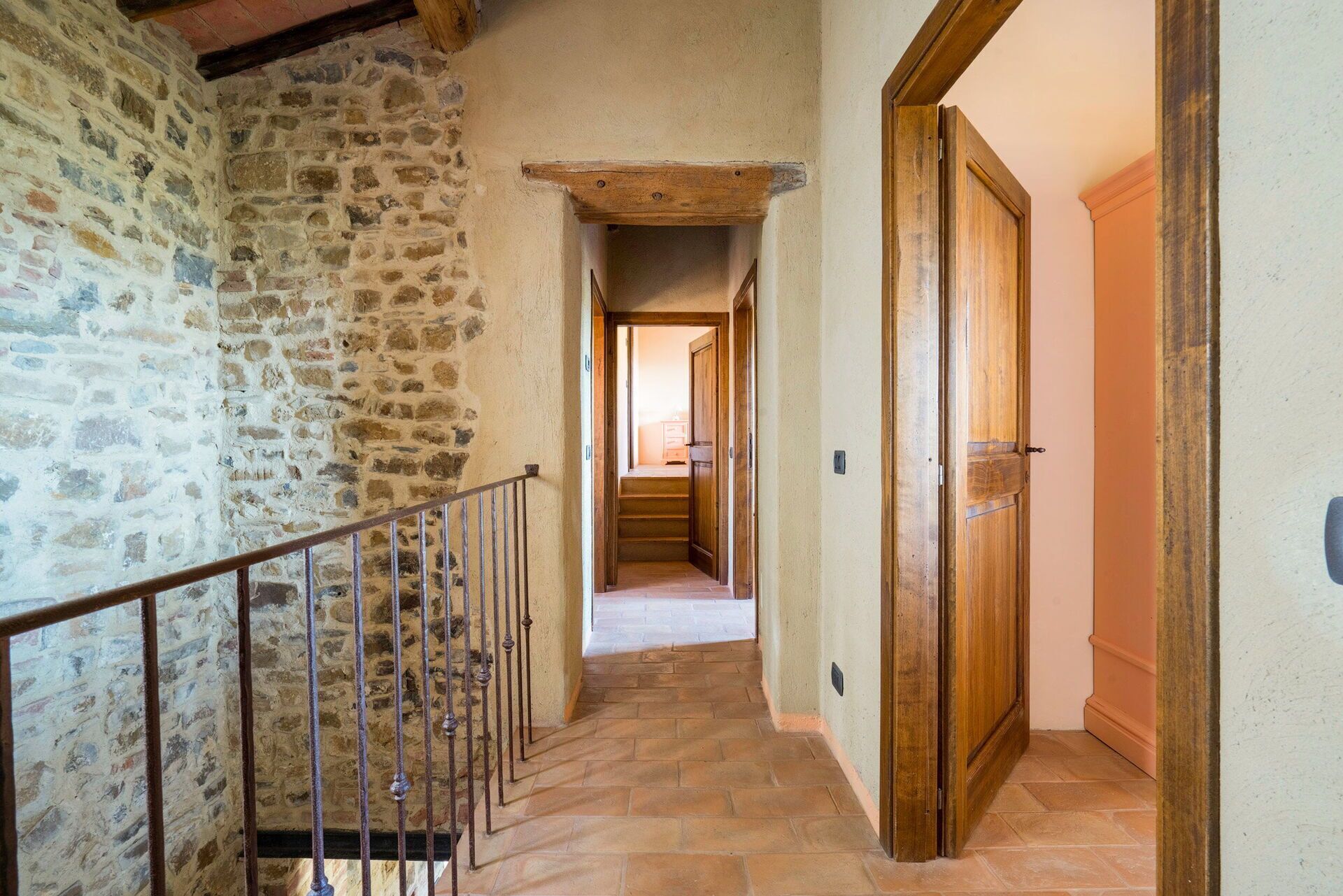 A stone wall, wooden door, and a staircase with metal railings.