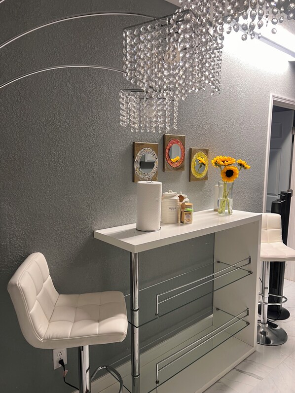Casa de banho moderna com toucador branco, prateleira de vidro e cadeira branca.