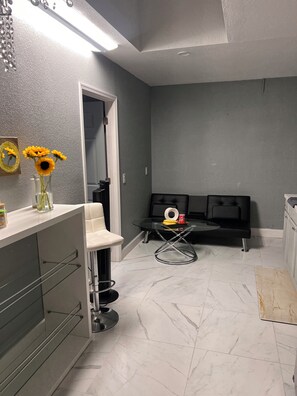 A modern bathroom with a white vanity, a glass table with a ring, and a mirror with a sunflower decoration.