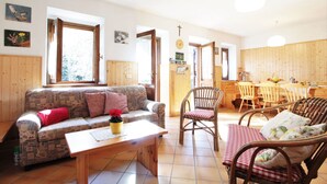 Ein gemütliches Wohnzimmer mit einer gemusterten Couch, einem Holztisch und Korbstühlen.