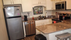 Una cocina moderna con electrodomésticos de acero inoxidable, armarios blancos y encimera de granito.