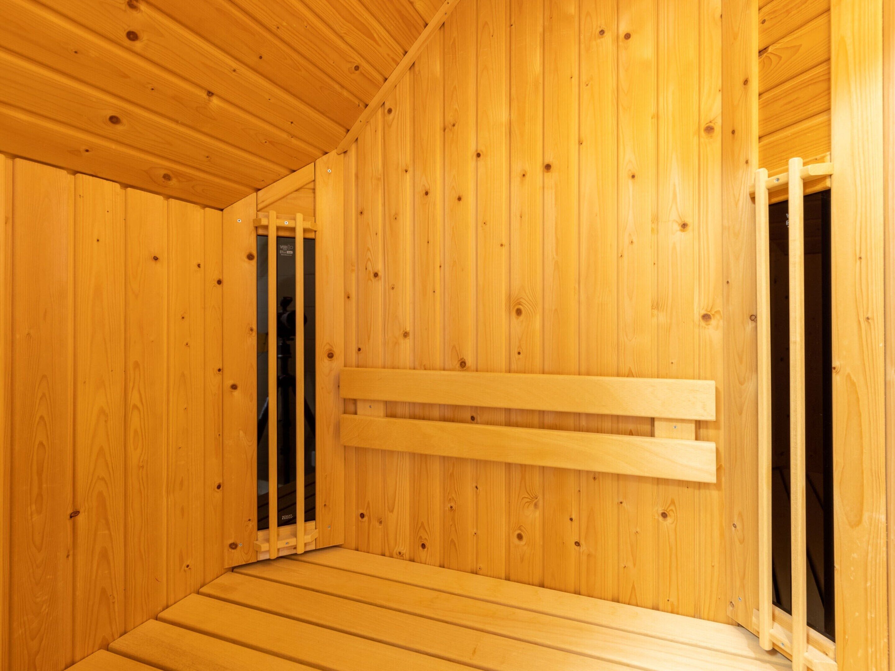 A wooden sauna room with a bench and a door.